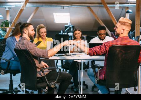 Freundliche Kollegen Faust stoßen, die in Büro- und feiert erfolgreiche Teamarbeit Stockfoto
