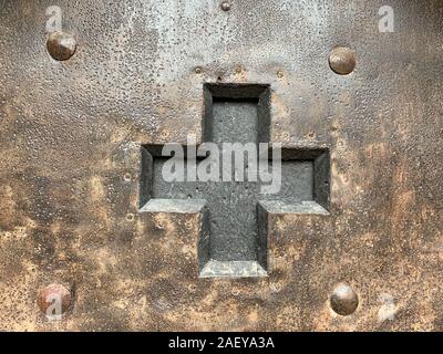 Ausgeschnitten schwarzes Kreuz in eine eiserne Tür mit Nieten, Nägel und Schrauben. Alten Beschlag aus dem Mittelalter, verwitterte, oxidiert und konserviert. Stockfoto