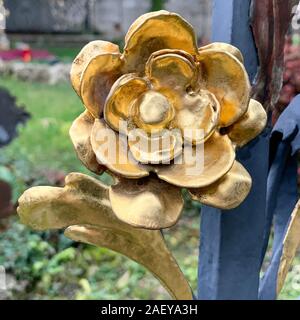 Rose Vergoldet aus Metall. Vergoldete blühen. Ornament auf einem eisernen Gitter eines Grabes aus dem neunzehnten Jahrhundert. Handgefertigte floralen Ornament. Stockfoto