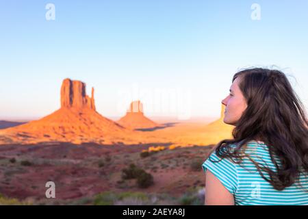 Junge Frau Mädchen an fäustlinge Suche butte Formationen mit rot orange Rock Farbe im Monument Valley Canyons bei Sonnenuntergang Sonnenlicht im Arizona Stockfoto