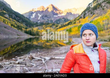 Maroon Bells See in Aspen, Colorado im Herbst bei Sonnenaufgang mit Frau kalt mit Hut stehend betrachten anzeigen Stockfoto