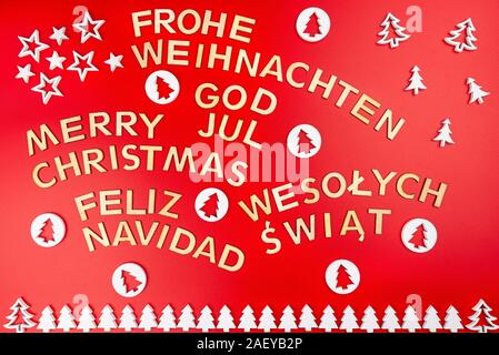 Aufschrift Frohe Weihnachten in Deutsch, Englisch, Polnisch, Schwedisch und Spanisch, liegend von oben. Von Holz- Inschriften, auf einem roten Bac isoliert Stockfoto