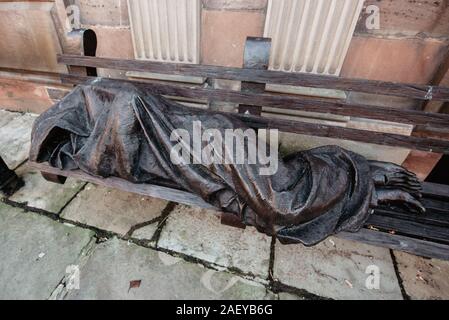 Jesus der Obdachlose, vom kanadischen Künstler Timothy Schmalz, stellt eine Figur dar, die auf einer Bank liegt. Seine durchbohrten Füße deuten darauf hin, dass es Jesus ist. Stockfoto