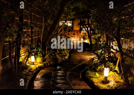 Kyoto, Japan Frühjahr leere Straße Garten in Gion Distrikt in der Nacht mit beleuchteten weiß grün Laternen auf nasser Straße weg Stockfoto