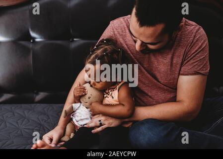 Vater Holding kostbare Multirassischen 2 Jahre altes Mädchen mit Puppe Stockfoto