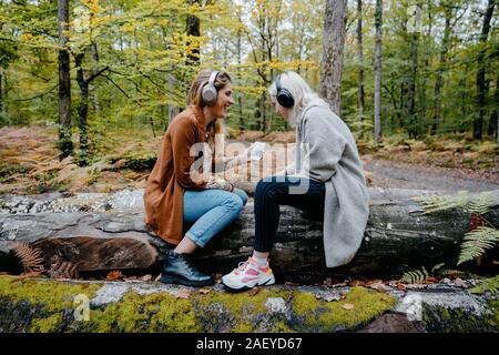 Zwei Frauen streaming Video auf einem Smartphone in einem abgelegenen Waldstück Stockfoto