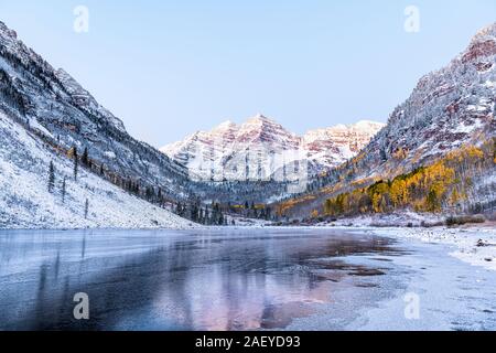 Maroon Bells Morgen Sonnenaufgang Reflexion mit Sonnenlicht auf Peak in Aspen, Colorado Rocky Mountain und Herbst gelb Laub und Schnee im Winter gefroren Stockfoto