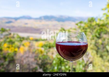 Rotwein Glas closeup und bokeh Hintergrund Blick auf Herbst Laub gelb Bäume in Aspen, Colorado Rocky Mountains Stockfoto
