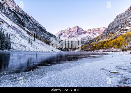 Maroon Bells sunrise Reflexion mit rosa Sonnenlicht auf Peak in Aspen, Colorado Rocky Mountain und Herbst gelb Laub und Schnee im Winter gefroren Lak Stockfoto