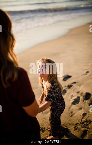 Tochter Mutter lächelnd am Strand bei Sonnenuntergang Stockfoto