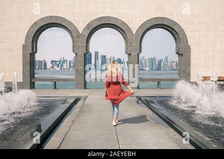 Rückansicht einer Frau gehen zwischen Brunnen und halten ihr Kleid Stockfoto