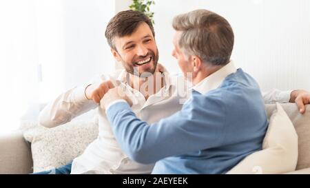 Reifer Mann und Vater stoßen die Fäuste auf dem Sofa zu Hause sitzen. Die Zeit mit älteren Elternteil. Panorama, selektiven Fokus Stockfoto