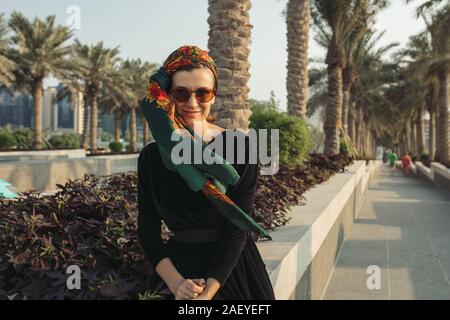 Junge Frau mit headwrap sitzen auf der Mauer in der Palm Gasse Stockfoto