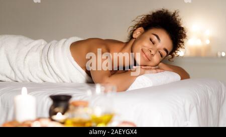 Wellness und Aromatherapie. Afrikanisch-amerikanische Frau entspannen mit Aroma Kerzen auf Fach in der Nähe Stockfoto