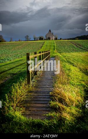 Ein holzzaun und der Weg zu einer ländlichen Kirche auf einem Hügel, St Huberts Kirche, Idsworth, Hampshire Stockfoto