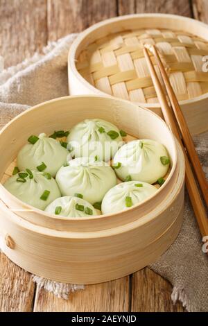 Der traditionellen chinesischen Baozi Dampf Brötchen in einem Bambus Dampferkorb close-up auf den Tisch. Vertikale Stockfoto