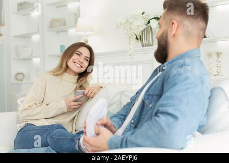 Liebevoller Mann tun Fuß massage für Ihre zarte Frau, entspannt auf einem Sofa zusammen Stockfoto