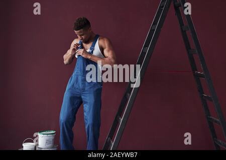 Das Tragen von Kleidung. Junge afrikanische amerikanische Arbeiter in der blauen Uniform haben einige Arbeit zu erledigen Stockfoto