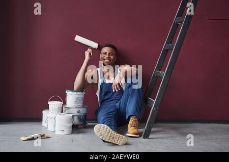 Gerne erledigt diese Aufgabe. Junge afrikanische amerikanische Arbeiter in der blauen Uniform haben einige Arbeit zu erledigen Stockfoto