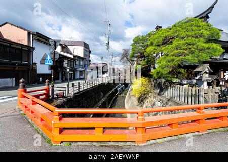 Takayama, Japan - April 9, 2019: Orange Brücke von Enako Fluss in der Präfektur Gifu in Japan mit gelben Baum Blumen im Frühling großem Betrachtungswinkel Stockfoto