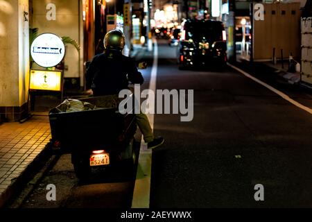 Kyoto, Japan - 9. April 2019: Gion bei Nacht mit Mann auf dem Motorrad mit Fahren auf der Strasse mit dem Verkehr Autos und Heineken Schild Stockfoto