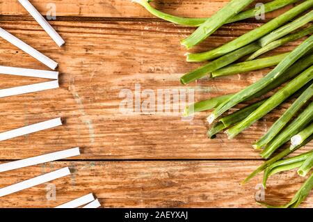 Konzepte der Raucherentwöhnung. Zigaretten und Schnittlauch auf grunge Holz Hintergrund angeordnet. Wahl zwischen gesunden Lebensstil und ungesunden Lebensstil. Stockfoto