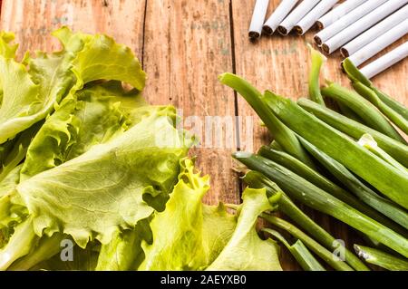 Zigaretten und Gemüse auf grunge Holz Hintergrund angeordnet. Konzepte der Raucherentwöhnung. Wahl zwischen gesunden Lebensstil und ungesunden Lebensstil. Stockfoto