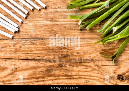 Konzepte der Raucherentwöhnung. Zigaretten und Schnittlauch auf grunge Holz Hintergrund angeordnet. Wahl zwischen gesunden Lebensstil und ungesunden Lebensstil. Stockfoto