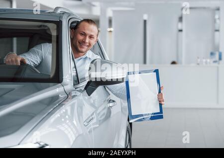 Immer glücklich, Sie zu sehen. Manager im modernen weißen Auto sitzen mit Papier und Dokumente in Händen Stockfoto