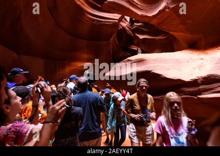 Seite, USA - 10. August 2019: Tour Gruppe von vielen Menschen innerhalb Upper Antelope Slot Canyon in Arizona Fotos mit Telefon aus Sandstein Formationen Stockfoto