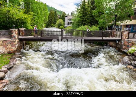 Vail, USA - 29. Juni 2019: im Europäischen Stil Resort Stadt Dorf in Colorado und Gore Creek Fluss Wasser unter Fuß-Brücke fließt Stockfoto