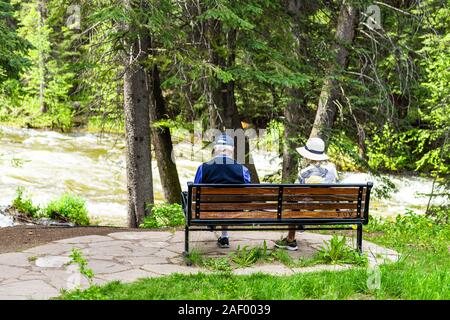 Vail, USA - 29. Juni 2019: Skiort in Colorado mit Senior Paar sitzt auf der Bank von Gore Creek River und Pinien Stockfoto