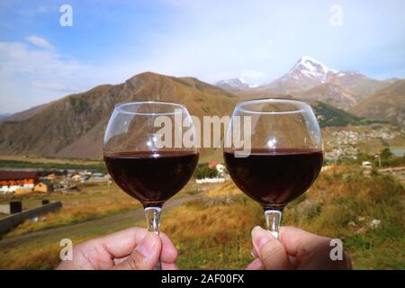 Zwei Gläser Rotwein in den Händen Feiern im Dorf Mount Kazbek Stockfoto