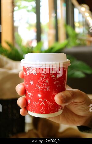 Vertikale Bild des Menschen Hand mit einem roten und weißen Tasse zum Mitnehmen Stockfoto