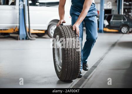 Auf dem Boden. Mitarbeiter in der blauen Uniform arbeitet im Automobil Salon Stockfoto