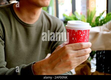 Junger Mann mit einem roten und weißen Takeaway Kaffeetasse in der Hand Stockfoto