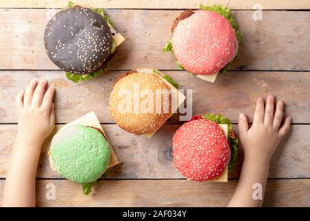 Kinder Hände und bunten bugerss mit selektiven Fokus auf den Vordergrund Burger, Ansicht von oben Stockfoto