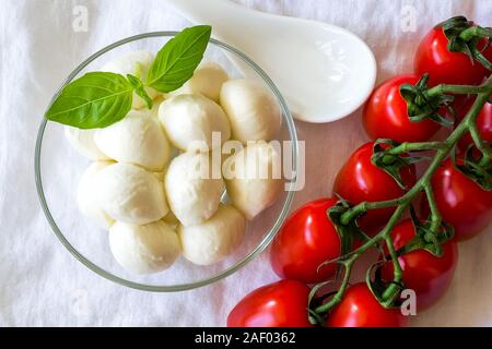 Mini mozzarella Kugeln in Glasschale und Niederlassung von Red Cherry Tomaten auf einem weißen Hintergrund. Healhy mediterrane Küche. Stockfoto