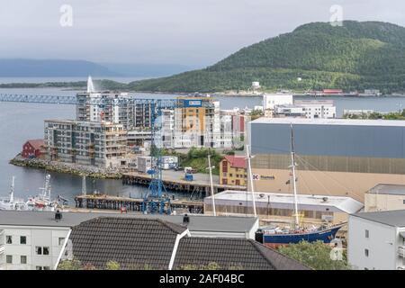 HARSTAD, Norwegen - 12. Juli 2019: Polarkreis fjord Stadtbild der kleinen Stadt Hafen mit neuen Gebäuden und alten Schiffen, unter hellen trübe Licht schoss auf Stockfoto