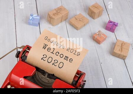 Urlaub Konzept - rot Schreibmaschine mit dem Text 'Auf Wiedersehen 2019 Willkommen 2020", Geschenkboxen auf weißem Holz- Hintergrund Stockfoto