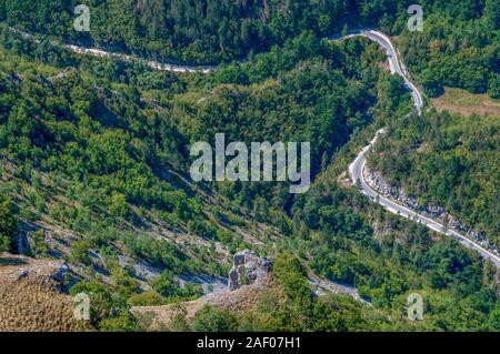 Eine kurvenreiche Bergstraße durch den Wald in extremen Höhen. Stockfoto
