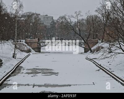 Fußgänger die Stadt Kanalkreuzung über eine Brücke in der Innenstadt von Riga an einem verschneiten März Tag nah an Ostern Stockfoto