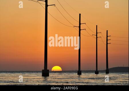 Elektrische Überlandleitungen über dem Atlantik, Silhouetted, während Golden Sunset, neben 7 Mile Bridge (Route 1), Marathon Key, Florida, USA Stockfoto