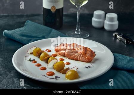 Eine große gebratenes Stück roter Fisch liegt auf einem weißen Teller mit Gemüse, eine schöne dienen in einem Restaurant. Stockfoto