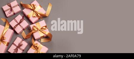 Ansicht von oben festliche Komposition mit schönen Geschenken in festlichen Papier gewickelt, Gold Ribbon und Gold Star Konfetti auf grauem Hintergrund. Stockfoto