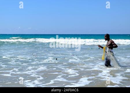 Afrikanische Fischer im flachen Wasser mit seinem fischernetz Stockfoto