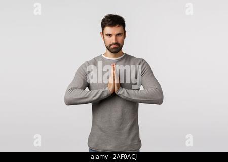 Zielstrebig und motiviert, gut aussehenden Bärtigen kaukasischen Kerl in graue Strickjacke, Höflich verbeugte sich mit Hände zusammen in Namaste gedrückt, asiatische Begrüßung Stockfoto