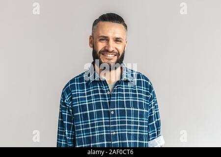 Reife bärtige Mann lächelte breit, stehend auf grauem Hintergrund Stockfoto