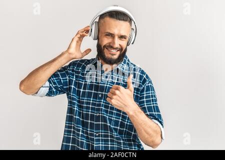 Nach bärtigen Mann in Kopfhörer mit Daumen hoch Stockfoto