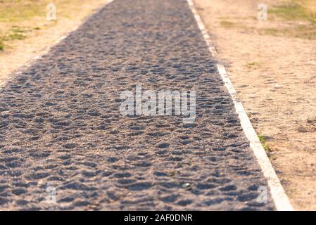 Ein Weg der kleine Steine. Grau Sand und Kies in einer verkehrsberuhigten Straße. Seltsame Fahrbahn. Stockfoto